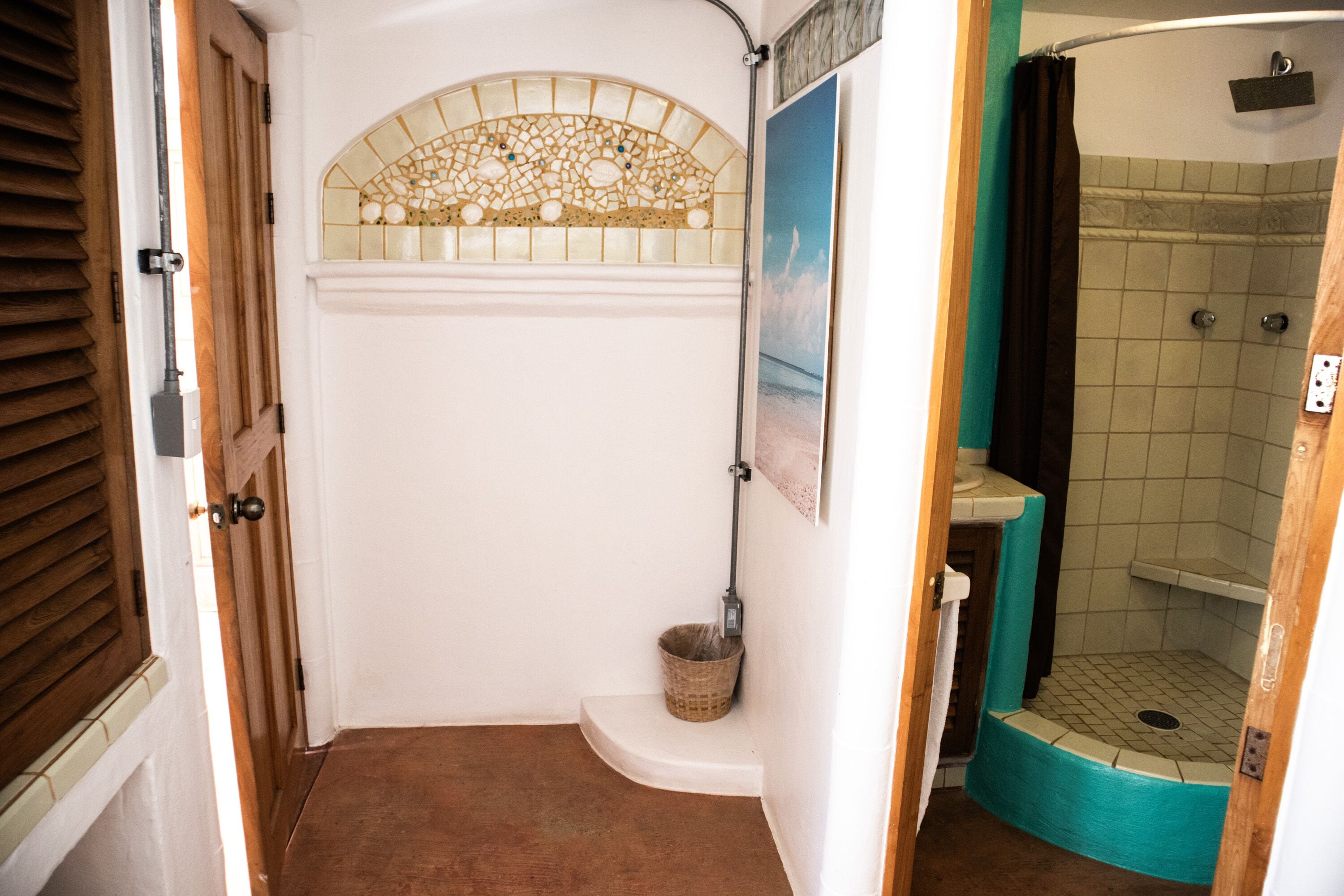 A bathroom with a shower, a small sink, and a decorative window.