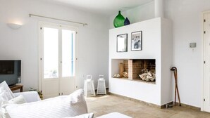 Ein modernes Wohnzimmer mit einem weißen Sofa, einem Kamin und einem Fernseher.