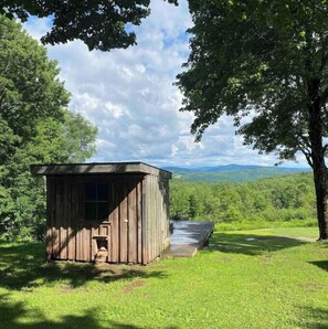 Situated in a lush landscape, this cabin features a simple roof and a small porch area surrounded by a well-maintained grassy space.