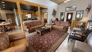 A spacious living room with leather sofas, a coffee table, and a patterned rug.