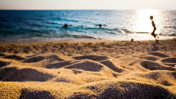 Una playa con dibujos en la arena y el océano al fondo.