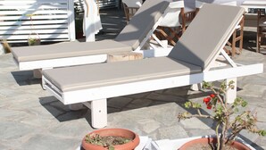 Un espacio al aire libre cubierto con sillones reclinables y macetas.