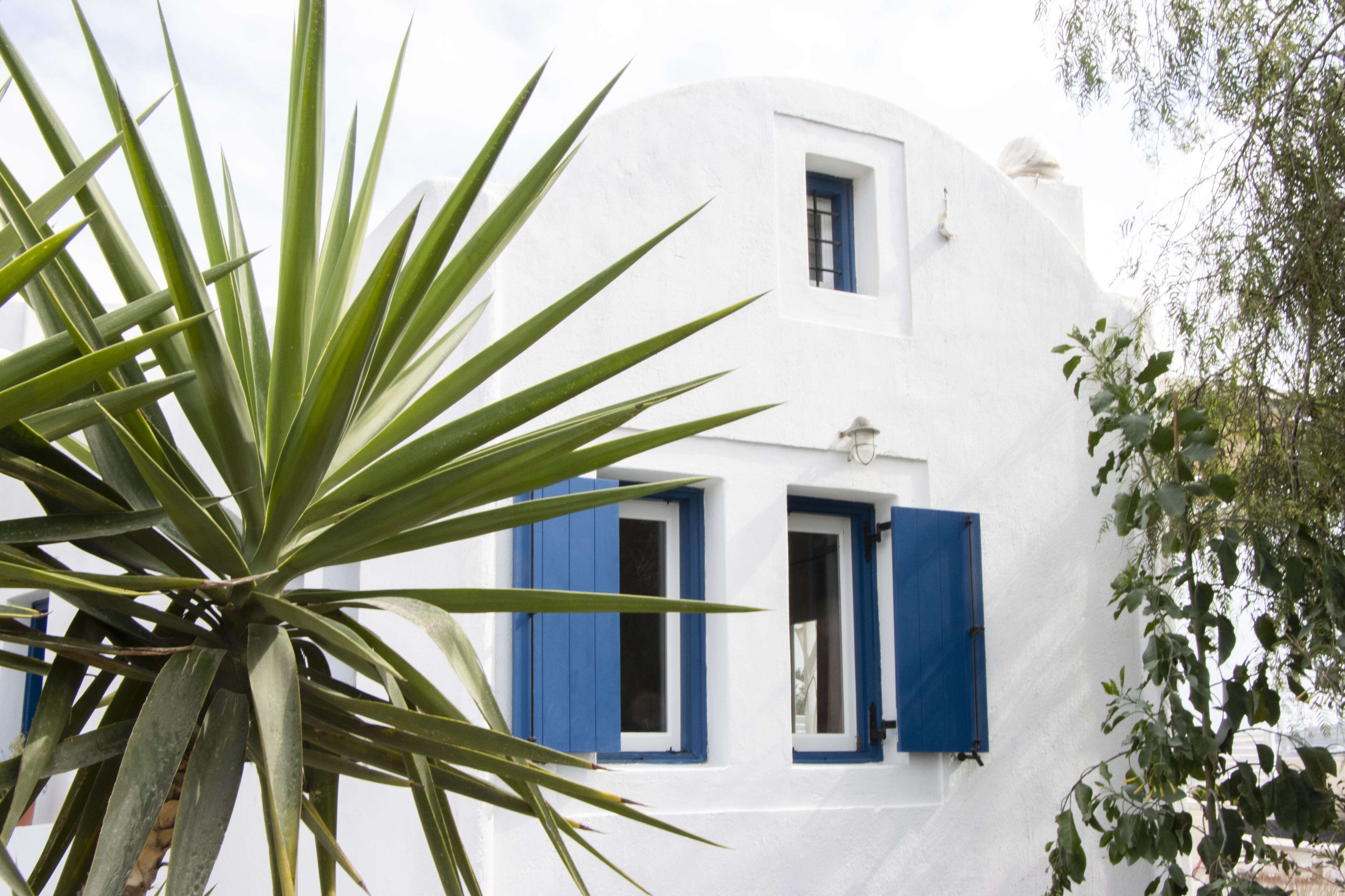 A white building with blue shutters and a small window.