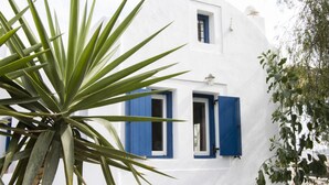 Un edificio blanco con contraventanas azules y una ventana pequeña.