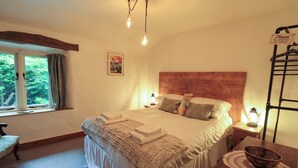Un lit bien fait, avec des oreillers et une couverture, une table de chevet avec une lanterne, une fenêtre avec des rideaux et une tête de lit en bois.