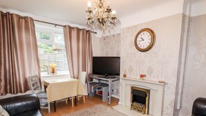 A living room with a fireplace, a television, a dining table, and leather sofas. - The Hawthorns (Chester)