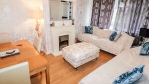 A cozy room with a fireplace, a sofa set, a dining table, and a chandelier. - The Hawthorns (Chester)