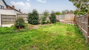 A backyard with a wooden fence, a small shed, and a tree. - The Hawthorns (Chester)