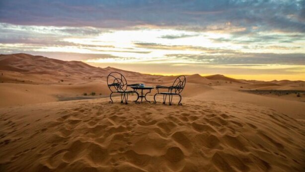 Wüstenlandschaft mit Tisch und zwei Stühlen im Vordergrund.