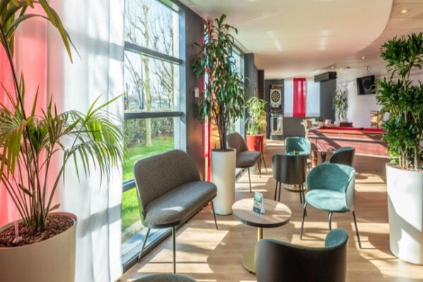 Un espacio interior moderno con ventanas amplias, plantas en macetas y muebles contemporáneos.