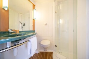 Un baño con cabina de ducha de vidrio, un lavabo con espejo y un inodoro.
