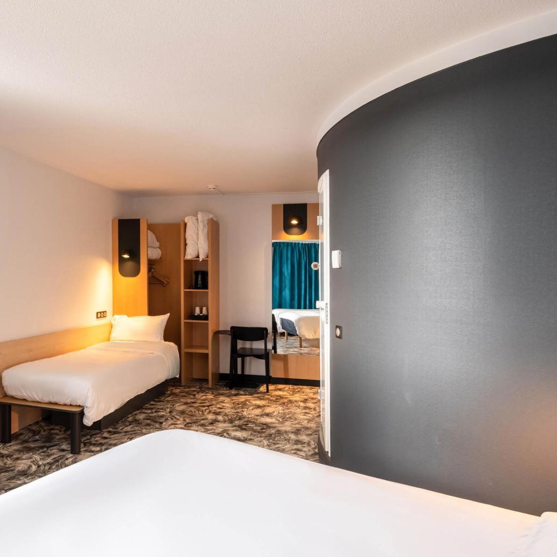 Habitación de hotel con dos camas, un armario, un escritorio y una silla.