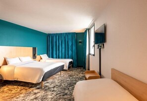 Quarto de hotel com duas camas, um espelho grande e uma televisão.