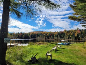 A lakeside view with chairs and a sign indicating no lifeguard on duty. - Ladd Pond Cabins and Campground (Colebrook)