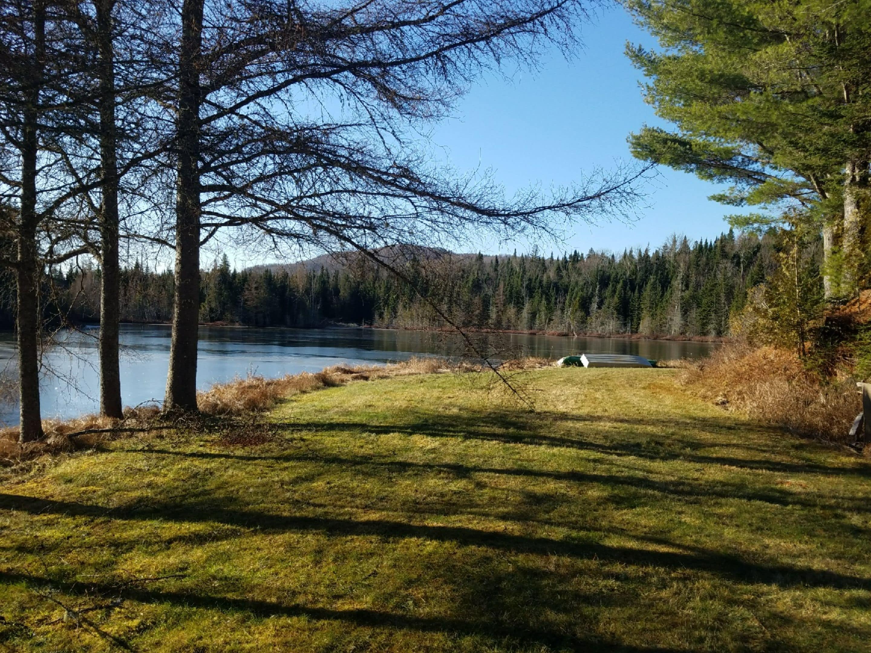 A natural landscape with a lake, trees, and a grassy area.