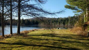 A natural landscape with a lake, trees, and a grassy area.