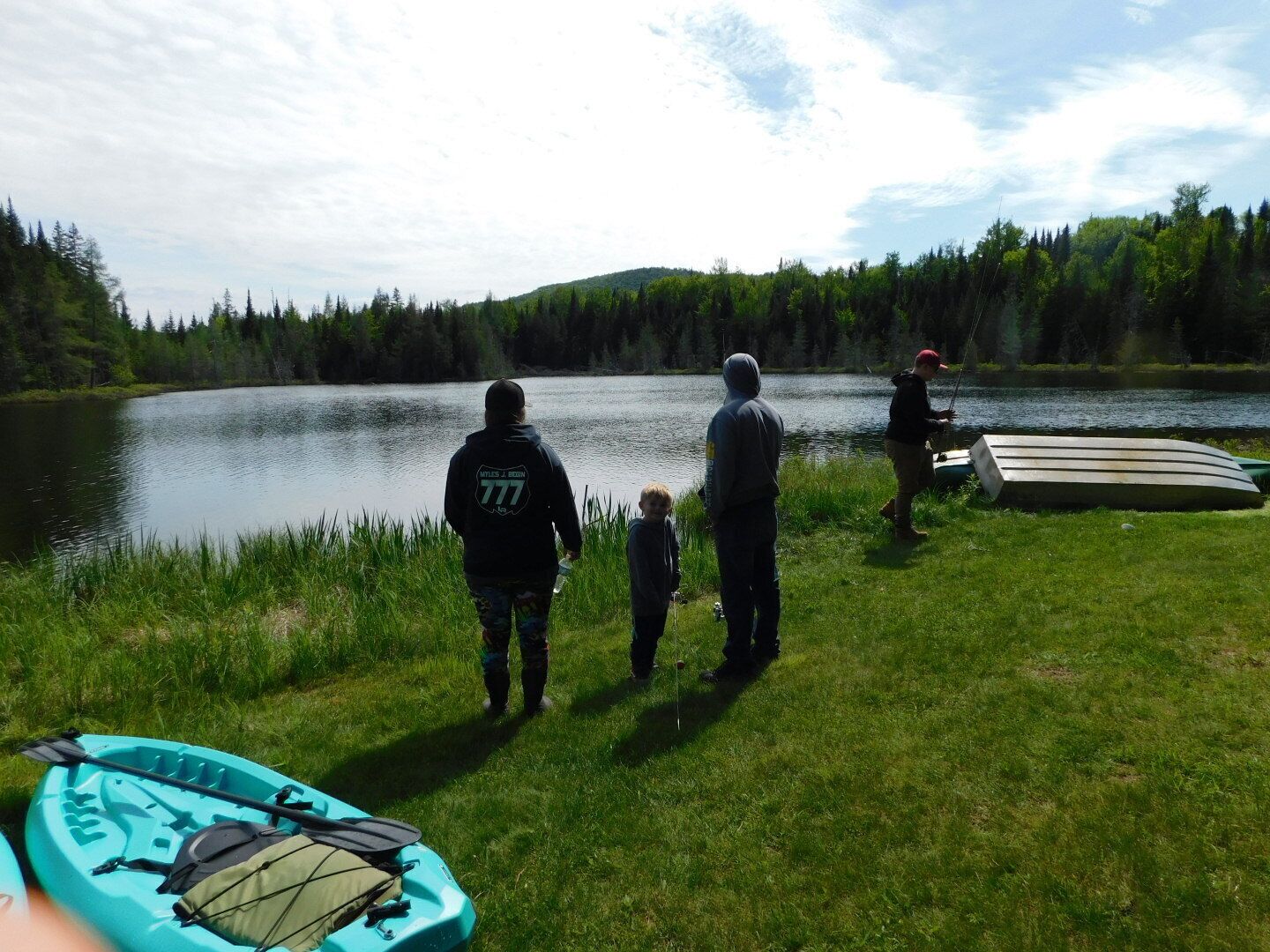 A group of people by a lake with kayaks and a canoe.