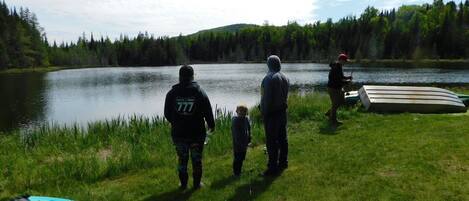 A group of people by a lake with kayaks and a canoe.