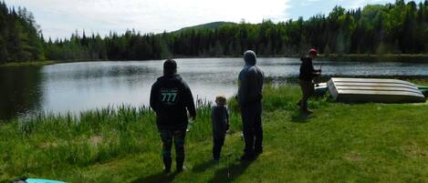 A group of people standing by a lake with kayaks and a canoe.