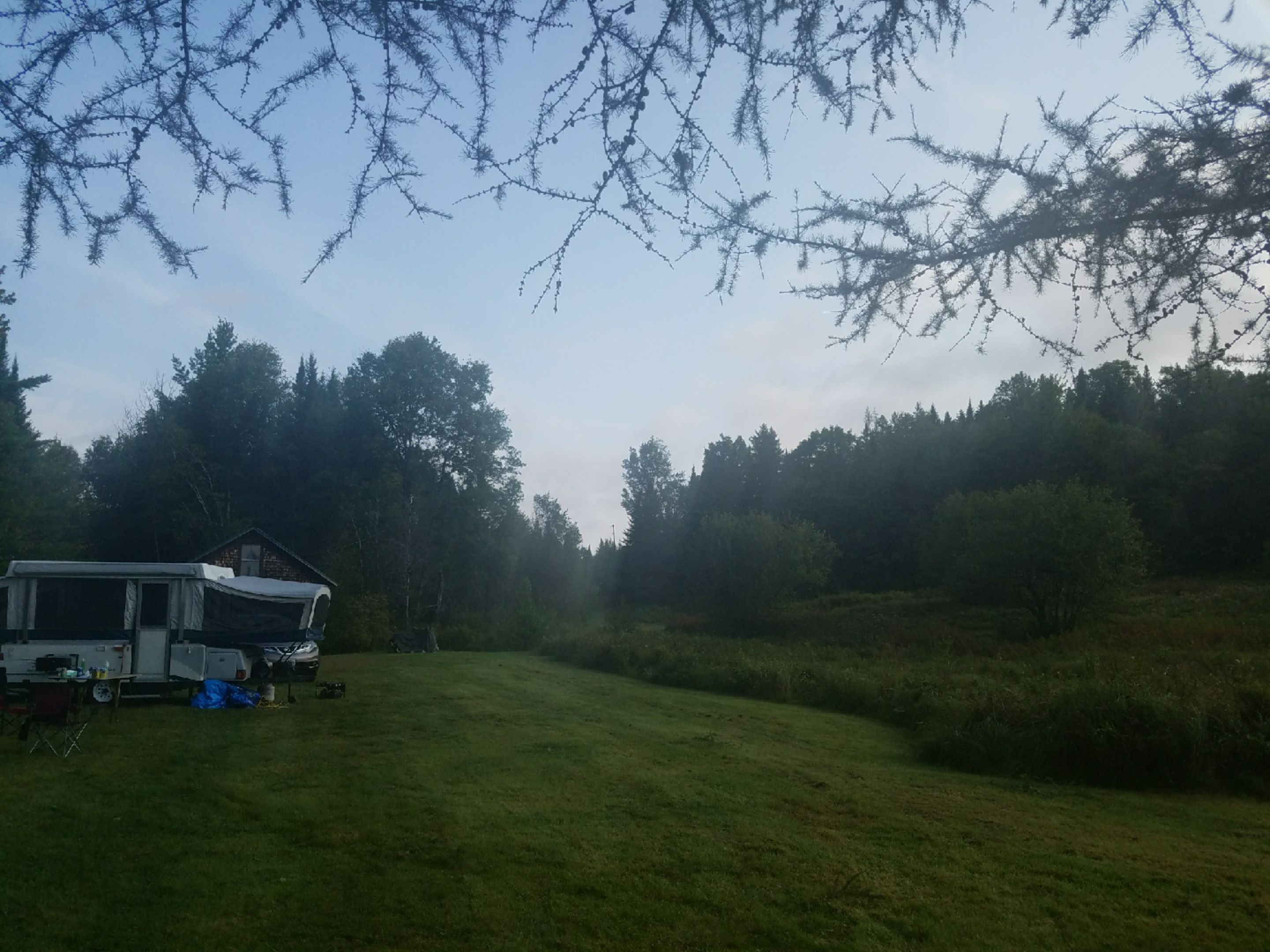 A campsite with a trailer and camping gear.