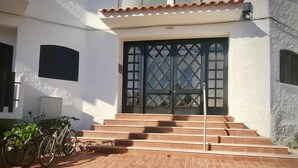 Una entrada de edificio con una escalera que conduce a una puerta con diseño de celosía. Bicicletas estacionadas a la izquierda de la entrada.
