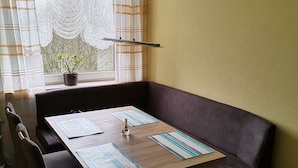 A dining area with a wooden table, black chairs, and a brown sofa. - FeWo - Feeling at home (Wilhelmshaven)