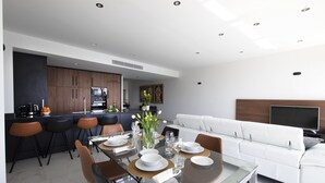 A modern living space with a dining area, kitchen, and seating area.