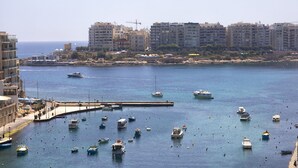 A marina with numerous boats docked, a pier, and a backdrop of buildings.