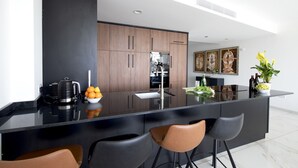 A modern kitchen with a black countertop, wooden cabinets, and a bar area with stools.