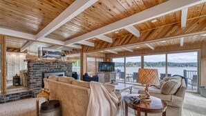 A spacious living room with a fireplace, large windows, and a view of the outdoors. - Private Beachfront Home w/ Hot Tub - Walk to Restaurants, Coffee and More! (Allyn)