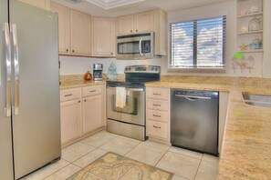 Kitchen features a large window with a view, light cabinetry, and stainless steel appliances.