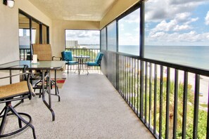Enjoy ocean views from this balcony with a table, chairs, and candle.