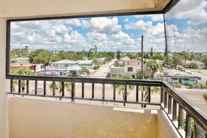 Enjoy the serene view from this balcony overlooking a residential area with palm trees and houses.