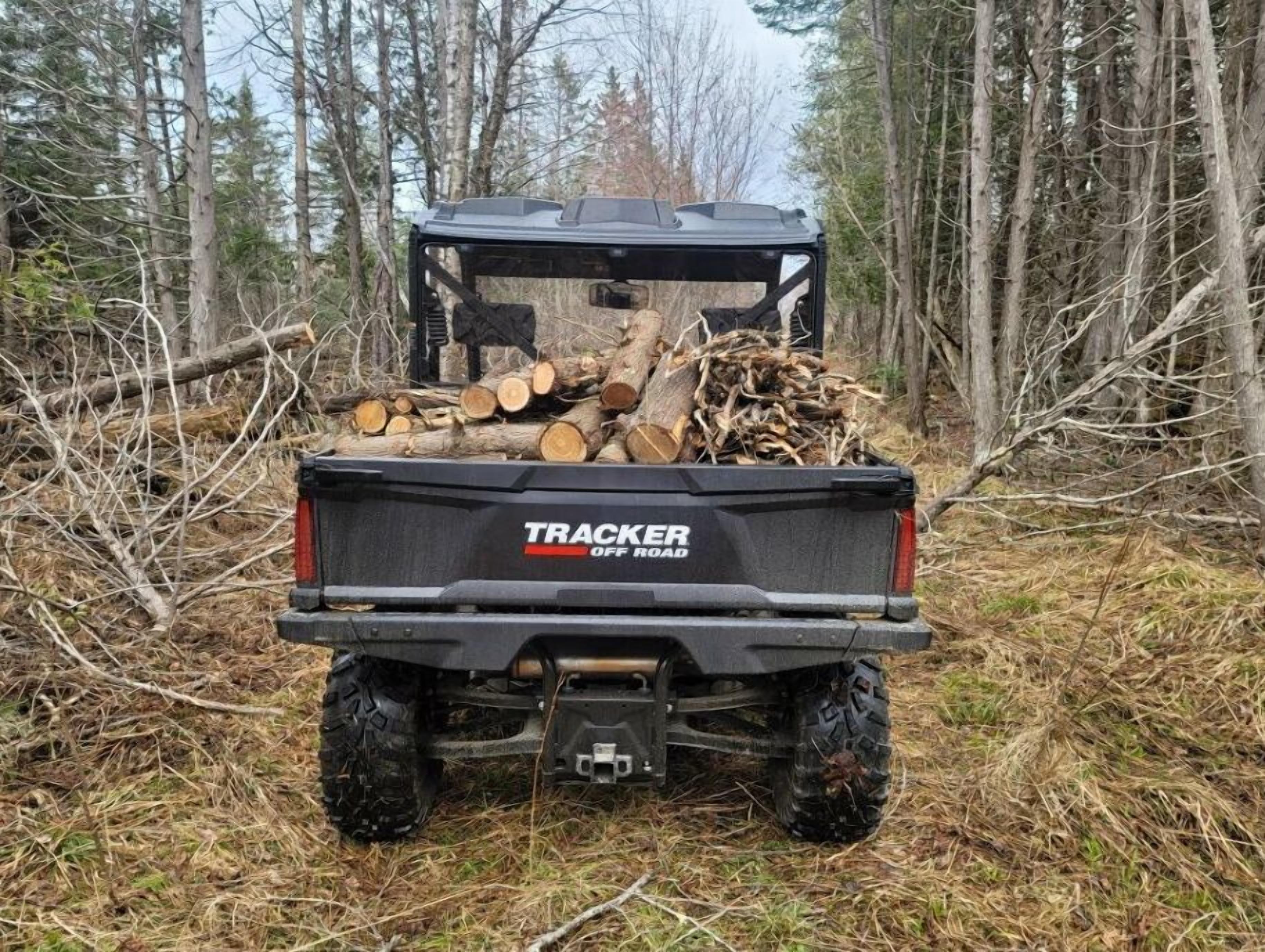 Et køretøj der transporterer et læs brænde, mærket 'TRACKER OFF ROAD'.