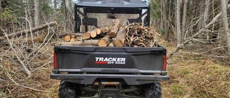Et køretøj der transporterer et læs brænde, mærket 'TRACKER OFF ROAD'.