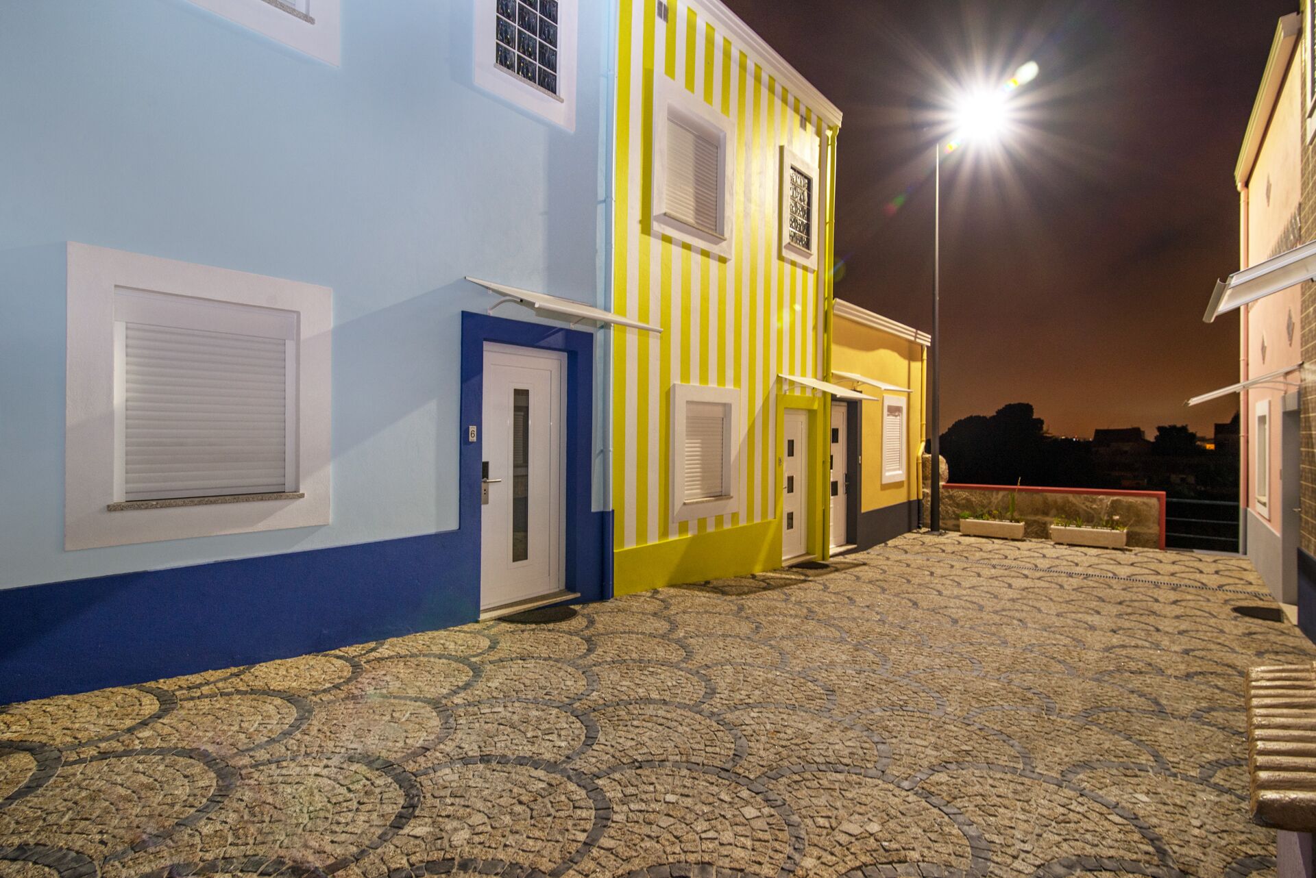 A courtyard with cobblestone flooring and buildings painted in blue and yellow.