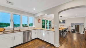 A spacious kitchen with white cabinetry, a stainless steel dishwasher, and a wooden countertop.