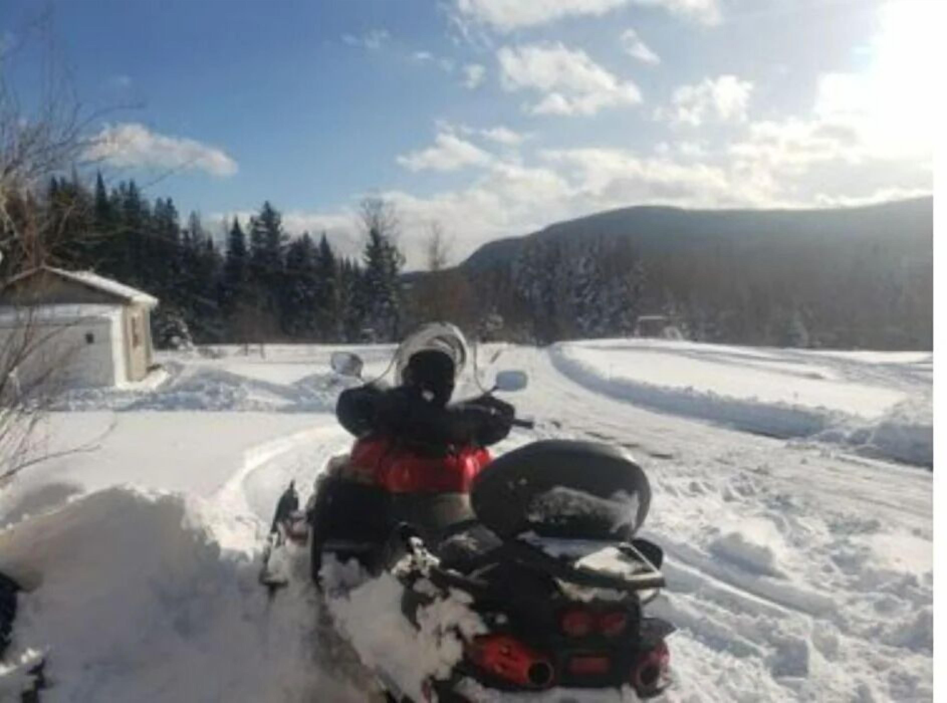 A snow-covered road with a motorcycle parked on the side.