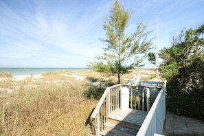 Stairs lead down to a serene beach area with a clear view of the surrounding waters.