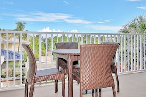Enjoy a peaceful retreat on the balcony with a table and two chairs, surrounded by lush palm trees and a residential view.