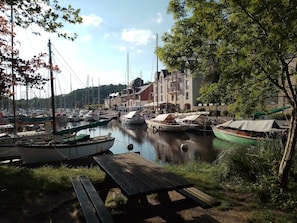 Un port de plaisance avec des bateaux amarrés, une jetée en bois et des bâtiments en arrière-plan.