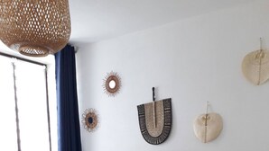 Een keurig opgemaakt slaapkamer met een groot bed, een rieten hoofdbord en decoratieve wandkunst.