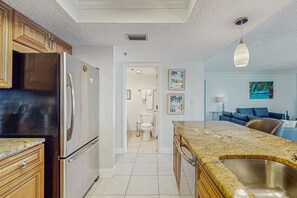 Kitchen features a refrigerator, sink, and dining area with a couch and table.