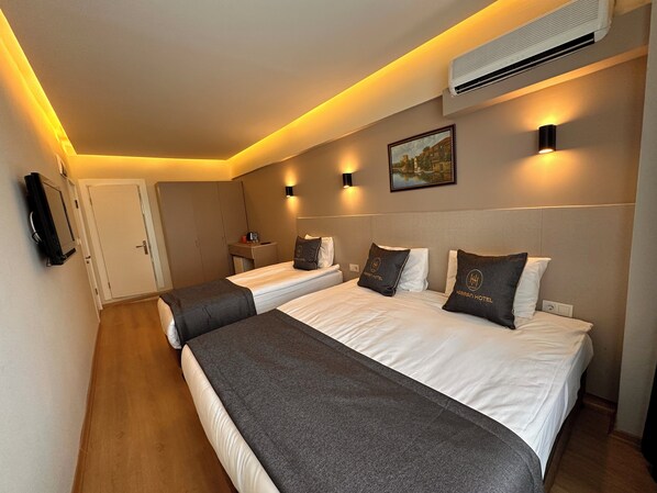 A hotel room with two beds, a desk, a chair, an air conditioner, and a painting on the wall.