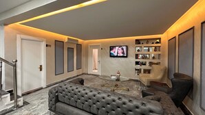 Uma sala de estar moderna com um sofá cinza estofado, uma mesa de centro e uma TV fixada na parede.