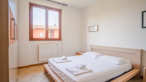 A bedroom with a bed, a window, a radiator, and a framed picture on the wall. - Garda Orange Apartment (Desenzano del Garda)