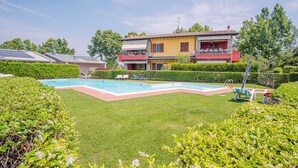 A residential property with a swimming pool, a well-maintained lawn, and a two-story house with a balcony. - Garda Orange Apartment (Desenzano del Garda)
