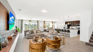 A modern living room with a sectional sofa, a dining area, and a kitchen.