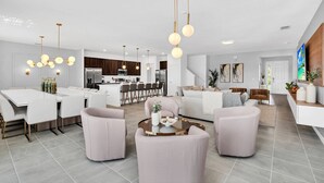 A modern living room with a dining area, kitchen, and a staircase leading to another level.
