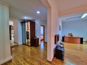 A spacious living area with a wooden floor, a large wooden cabinet, a television, and a desk with a chair. - Spacious Apartment In The Centre Of The Capital (Bucharest)